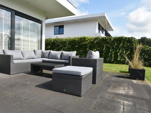 eine Terrasse mit einem Sofa, einem Tisch und Stühlen in der Unterkunft Holiday Home in Zeewolde with Jetty next to golf course in Zeewolde