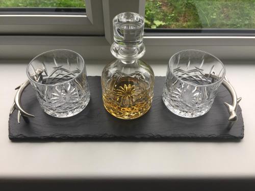 three glasses and a bottle on a black tray at Glenfalloch Beag Apartment, Torvaig in Portree