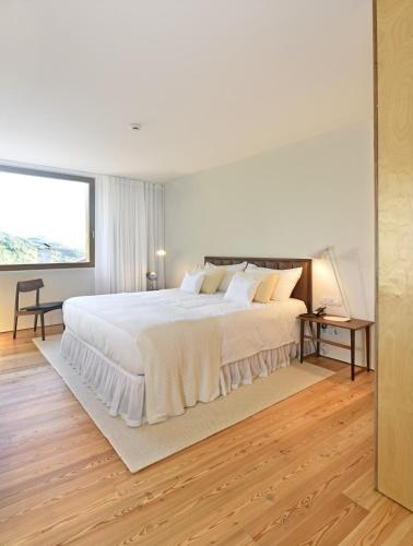 a white bedroom with a large bed and a window at Casas Da Lapa, Nature & Spa Hotel in Seia