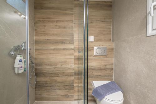 a bathroom with a toilet and a glass shower at Athens Bright Suite by CloudKeys in Athens