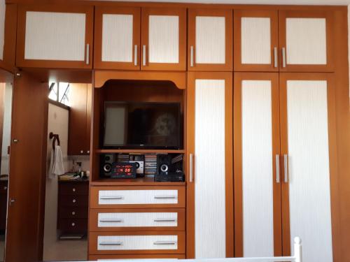 a living room with a tv and a wooden cabinet at Hosts in Rio Homestay in Rio de Janeiro