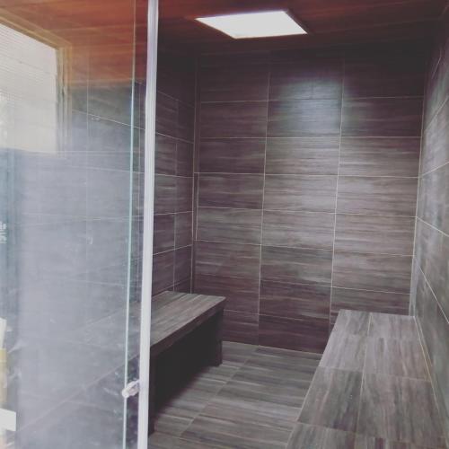 a shower with a wooden bench in a room at Hostal spa casa de piedra con jacuzzi in Santa Rosa de Cabal