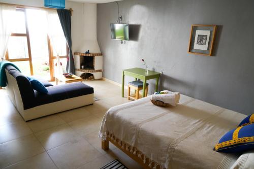 a bedroom with a bed and a couch and a table at Gaia Guest House in San Cristóbal de Las Casas