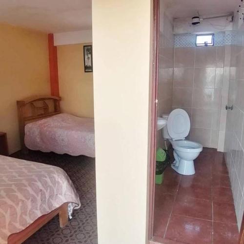 2 fotos de un baño con aseo y un dormitorio en Hostal Puerto Alegre, en Copacabana