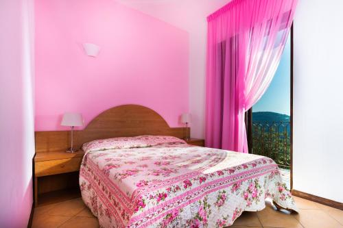 a pink bedroom with a bed and a window at L'Ulivo Resort in Vico Equense