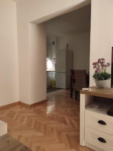 a living room with a wooden floor and a kitchen at Apartman Olga in Trebinje