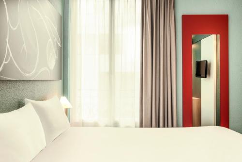a bedroom with a white bed and a window at ibis Paris Boulogne Billancourt in Boulogne-Billancourt