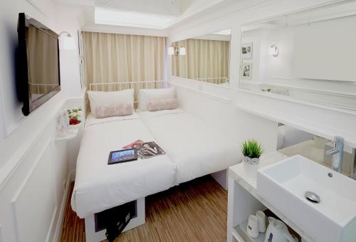 a white bedroom with a bed and a sink at Mini Hotel Causeway Bay in Hong Kong