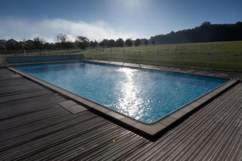 une grande piscine sur une terrasse en bois dans l'établissement Domaine du Bel Air, à Bar-sur-Seine