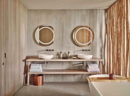 a bathroom with two sinks and two mirrors at Patina Maldives, Fari Islands in North Male Atoll