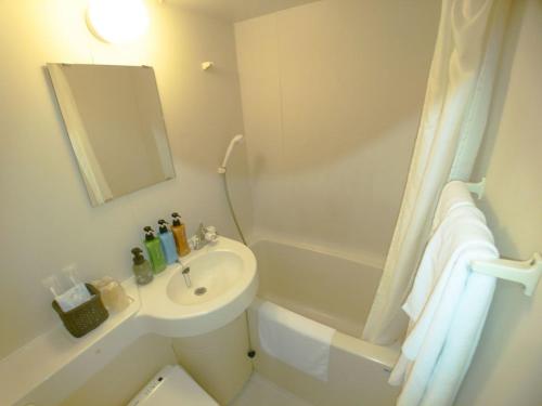 a white bathroom with a sink and a bath tub at Sky Heart Hotel Hakata in Fukuoka