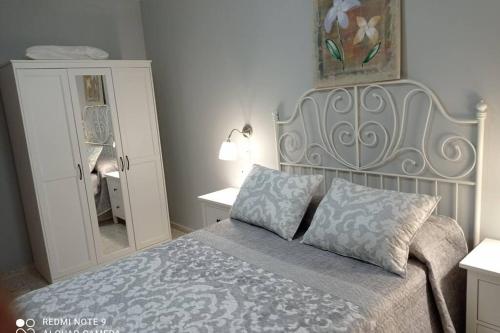 1 dormitorio con 1 cama grande y espejo en Apartamento cabañiles wifi, en Jerez de la Frontera