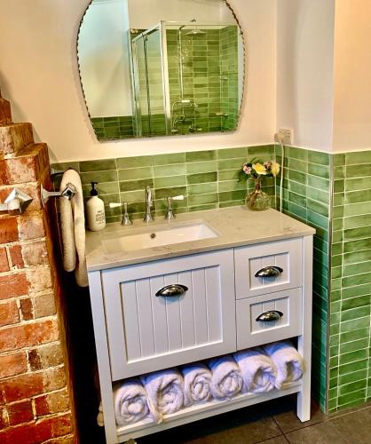 a bathroom with a sink and a mirror at Sinnamons Cottage in Maldon