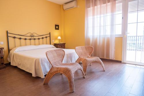 a bedroom with a bed with two chairs and a window at Casa en el pantano de Orellana in Orellana la Sierra