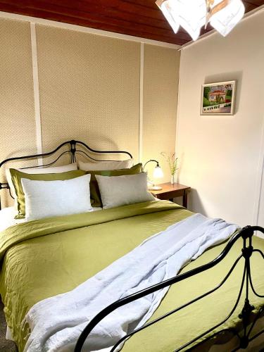 a bedroom with a large green bed with pillows at Sinnamons Cottage in Maldon