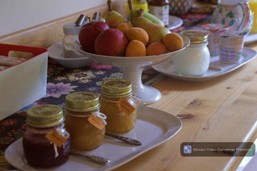 una mesa con tarros de mermelada y un bol de fruta en Casa Acquariana, en Belluno