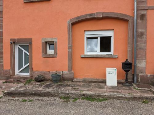 un edificio naranja con dos ventanas y un contador en Le Petit Moulin, en Fouday