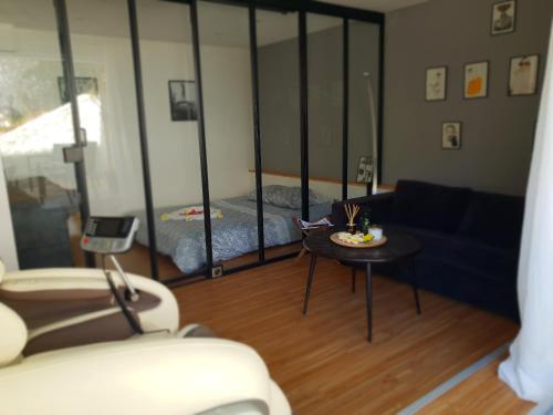 a living room with a couch and a table at Suite room jacuzzi sauna privatif illimité Clisson in Clisson
