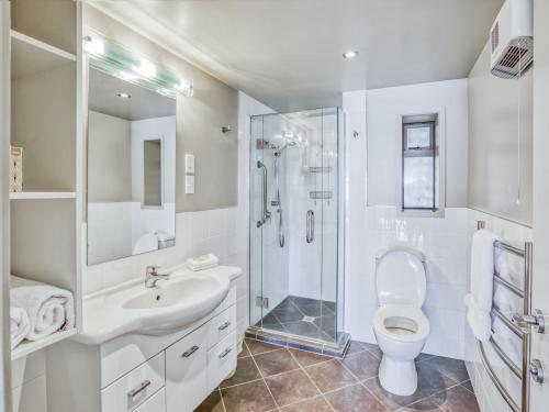 a white bathroom with a shower and a toilet at Ika Nui Taupo in Taupo