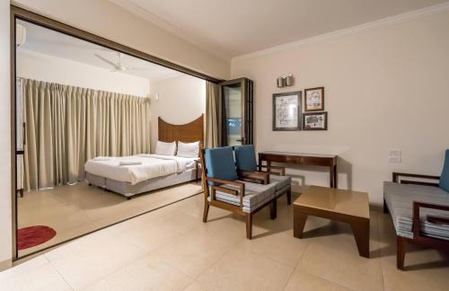 ein Schlafzimmer mit einem Bett, einem Stuhl und einem Sofa in der Unterkunft Casa Legend Suites Candolim Goa in Candolim