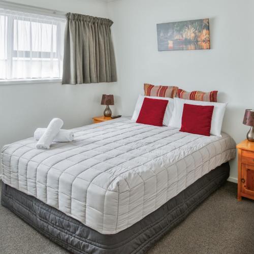 a bedroom with a large white bed with red pillows at Ika Nui Taupo in Taupo