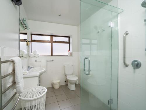 a bathroom with a toilet and a glass shower at Ika Nui Taupo in Taupo