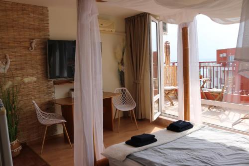 a bedroom with a bed and a balcony with a television at Fort Noxs, Sea Together in Elenite