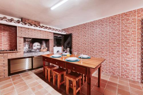 a dining room with a wooden table and a brick wall at Casa da Pedra by Amazing Madeira in Santana