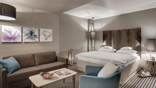 a bedroom with a bed and a living room with a couch at INNs HOLZ in Ulrichsberg
