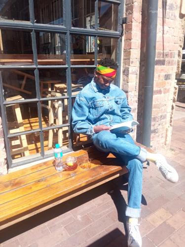 a man sitting on a bench reading a book at Maboneng City Building Free WiFi and Swimming pool in Johannesburg