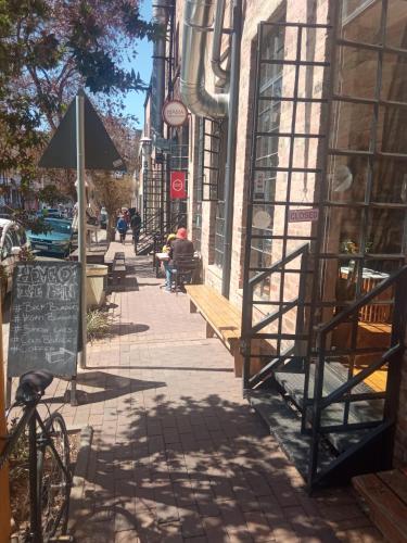 a street with people sitting on benches on a sidewalk at Maboneng City Building Free WiFi and Swimming pool in Johannesburg
