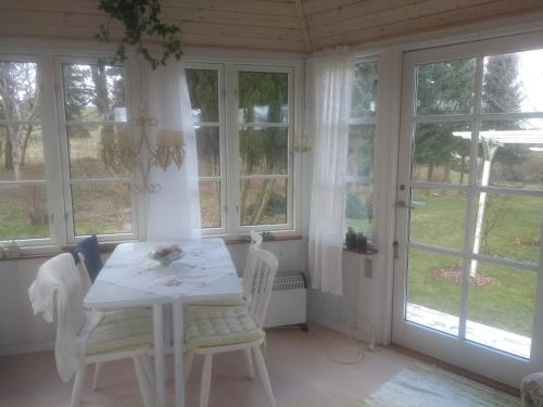 a dining room with a table and chairs and windows at Romantik og idyl in Dybvad