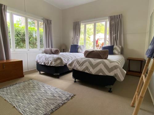 1 dormitorio con 2 camas y 2 ventanas en Miss Bullens Cottage, en Yungaburra