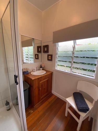 Baño pequeño con lavabo y espejo en Miss Bullens Cottage, en Yungaburra