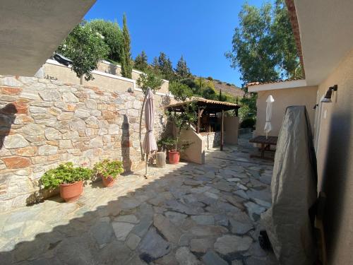 a stone courtyard with an umbrella and potted plants at Luxury villa with stunning panoramic sea view in Keratea
