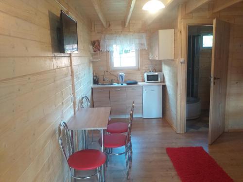 a kitchen with a table and chairs in a cabin at Domki i pokoje ,,Pod Palmami" w centrum in Okuninka