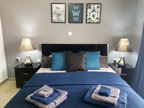 a bedroom with a blue bed with towels on it at Panorama Village Complex in Paralimni