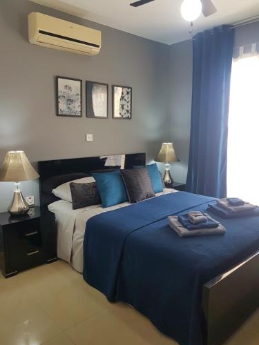 1 dormitorio con 2 camas con sábanas azules y ventana en Panorama Village Complex en Paralimni