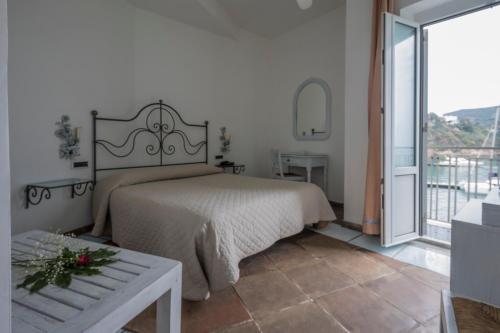 1 dormitorio con 1 cama grande y balcón en Hotel Gennarino A Mare, en Ponza