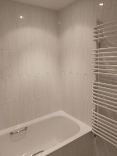 baño blanco con bañera y pared de azulejos blancos en Chauffeur's, Snape, en Saxmundham