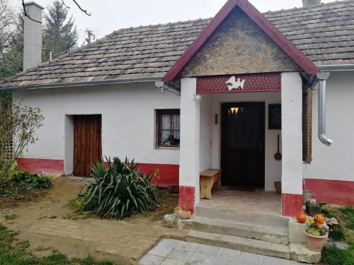 ein weißes und rotes Haus mit einer schwarzen Tür in der Unterkunft Traditionelles Bauernhaus Flieder in Zalaszentgrót