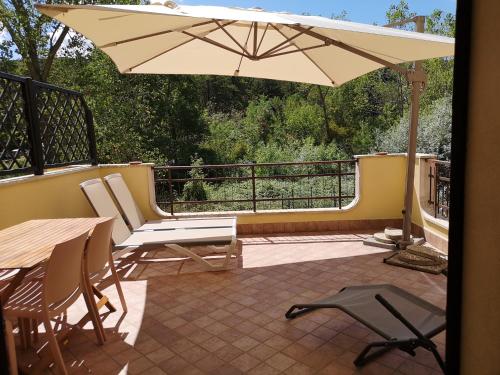 patio z parasolem, stołem i krzesłami w obiekcie Villa Terrena w mieście Bagni San Filippo