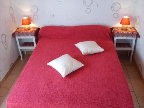 - un lit rouge avec 2 oreillers blancs dans l'établissement Le Gite de Colette et Jean-Claude, à Naujac-sur-Mer