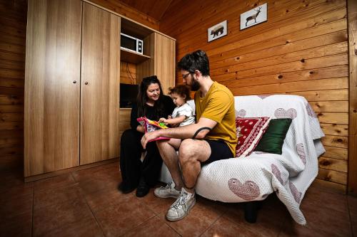 a man and a woman and a child sitting on a bed at Villaggio Gofree in Pragelato