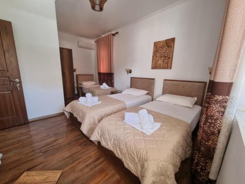 2 bedden in een hotelkamer met houten vloeren bij HOTEL VILA TWIX in Berat