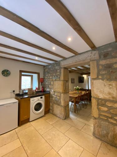 a kitchen with a washing machine and a stone wall at The Barn in Bedale