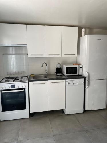 eine Küche mit weißen Geräten und weißen Schränken in der Unterkunft 61 BIS ST GEORGES DE DIDONNE in Saint-Georges-de-Didonne