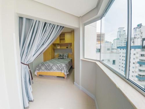 a bedroom with a bed and a large window at Apartamento Pontal Norte Ao Lado Da Big Wheel in Balneário Camboriú