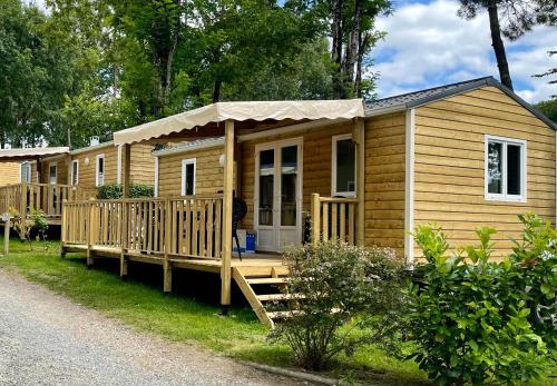 eine Holzhütte mit einer Veranda und einer Terrasse in der Unterkunft Camping Paradis Le Pressoir in Petit-Palais-et-Cornemps