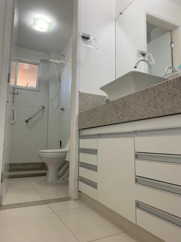 a white bathroom with a sink and a toilet at Apto 2 Quartos Perfeito in Guarapari